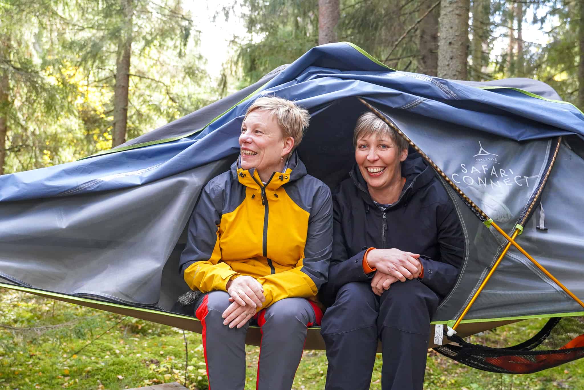 Kaksi naista puihin kiinnitetyssä teltassa.
