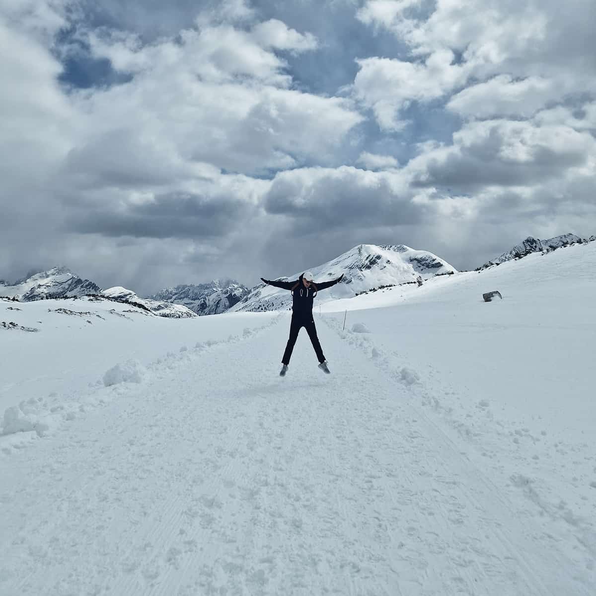 Poika hyppää ilmaan lumisessa maisemassa.