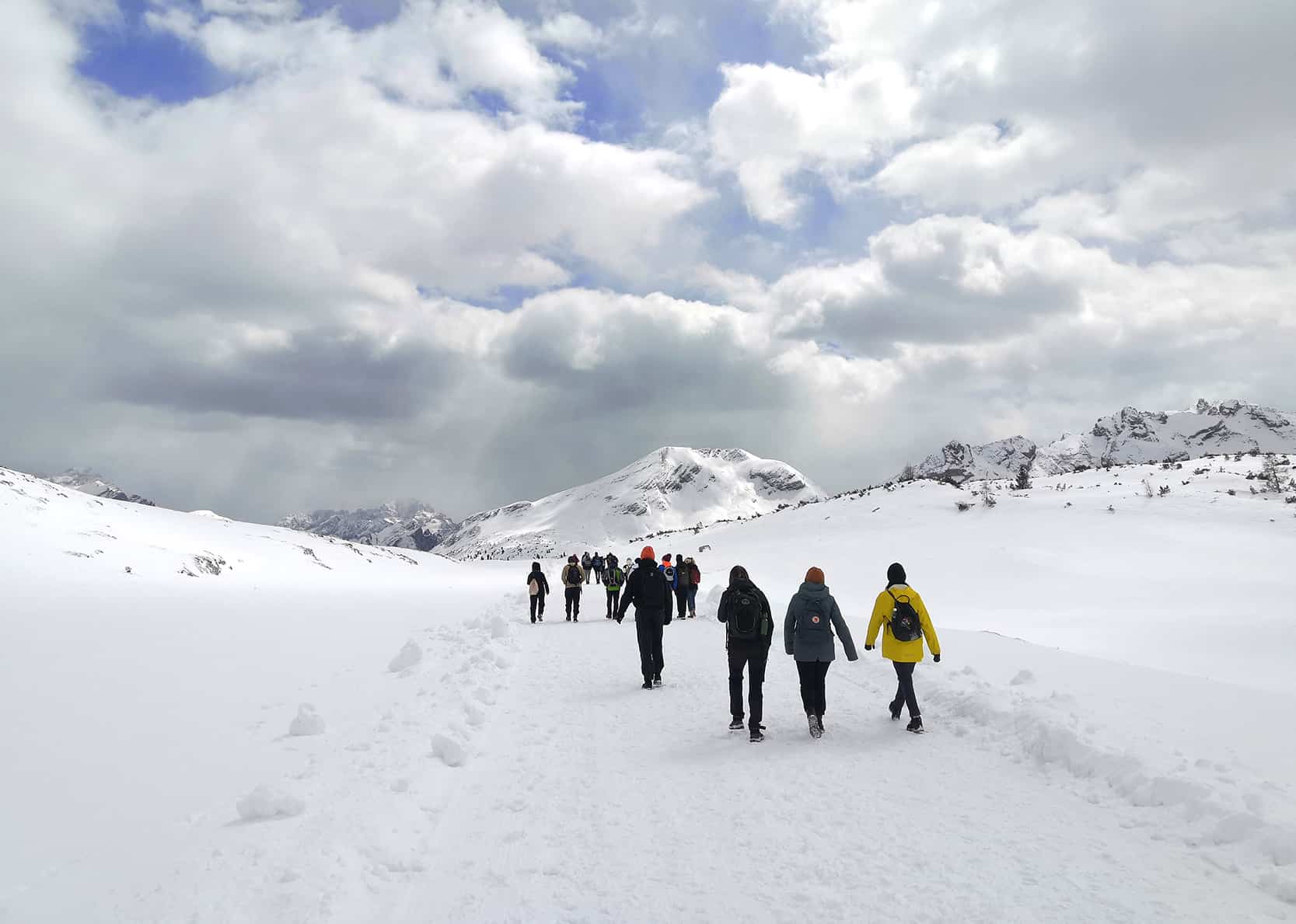 Joukko ihmisiä patikoi lumisilla Alpeilla.
