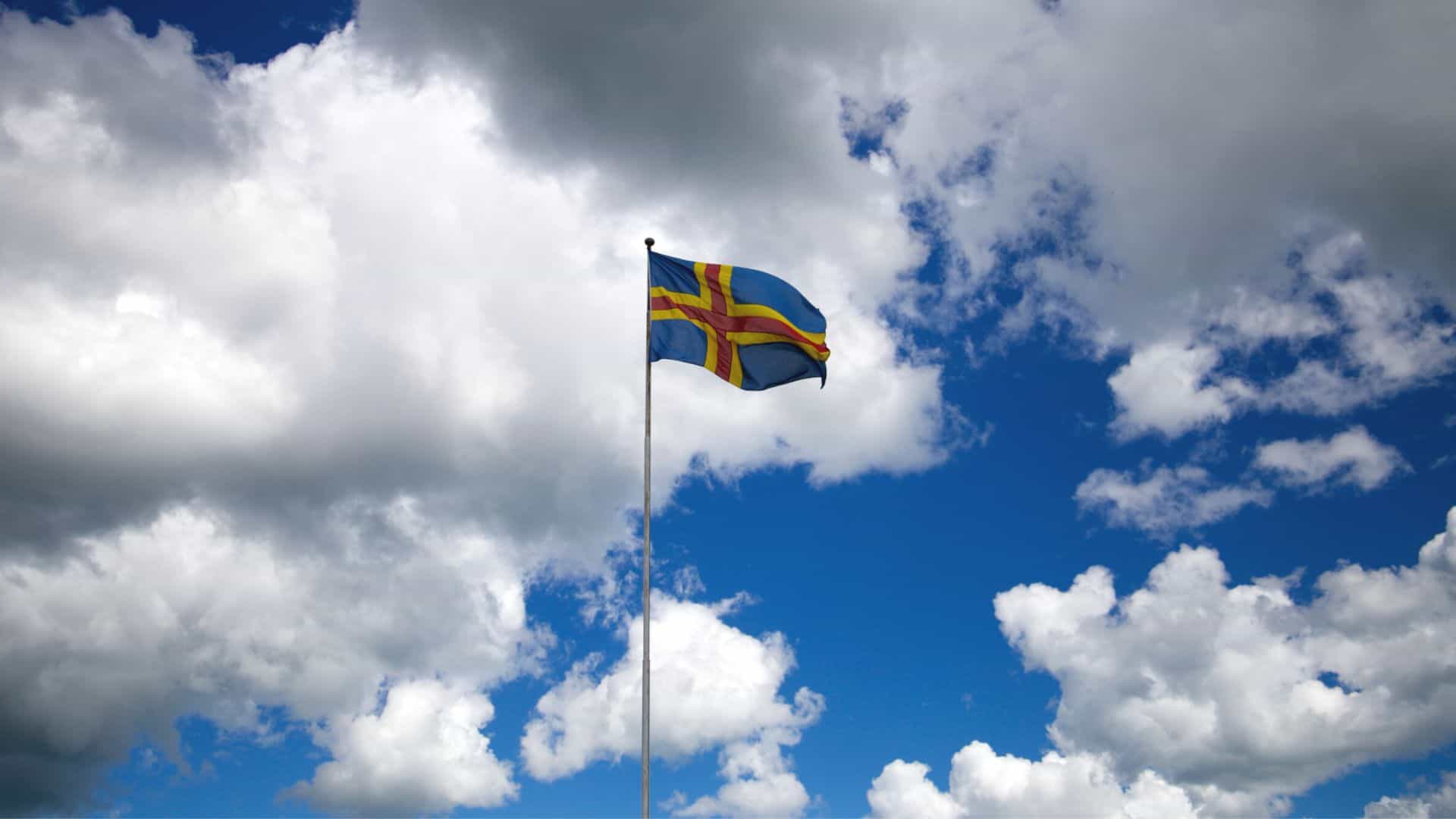 Ahvenanmaan lippu kuvattuna taivasta vasten.