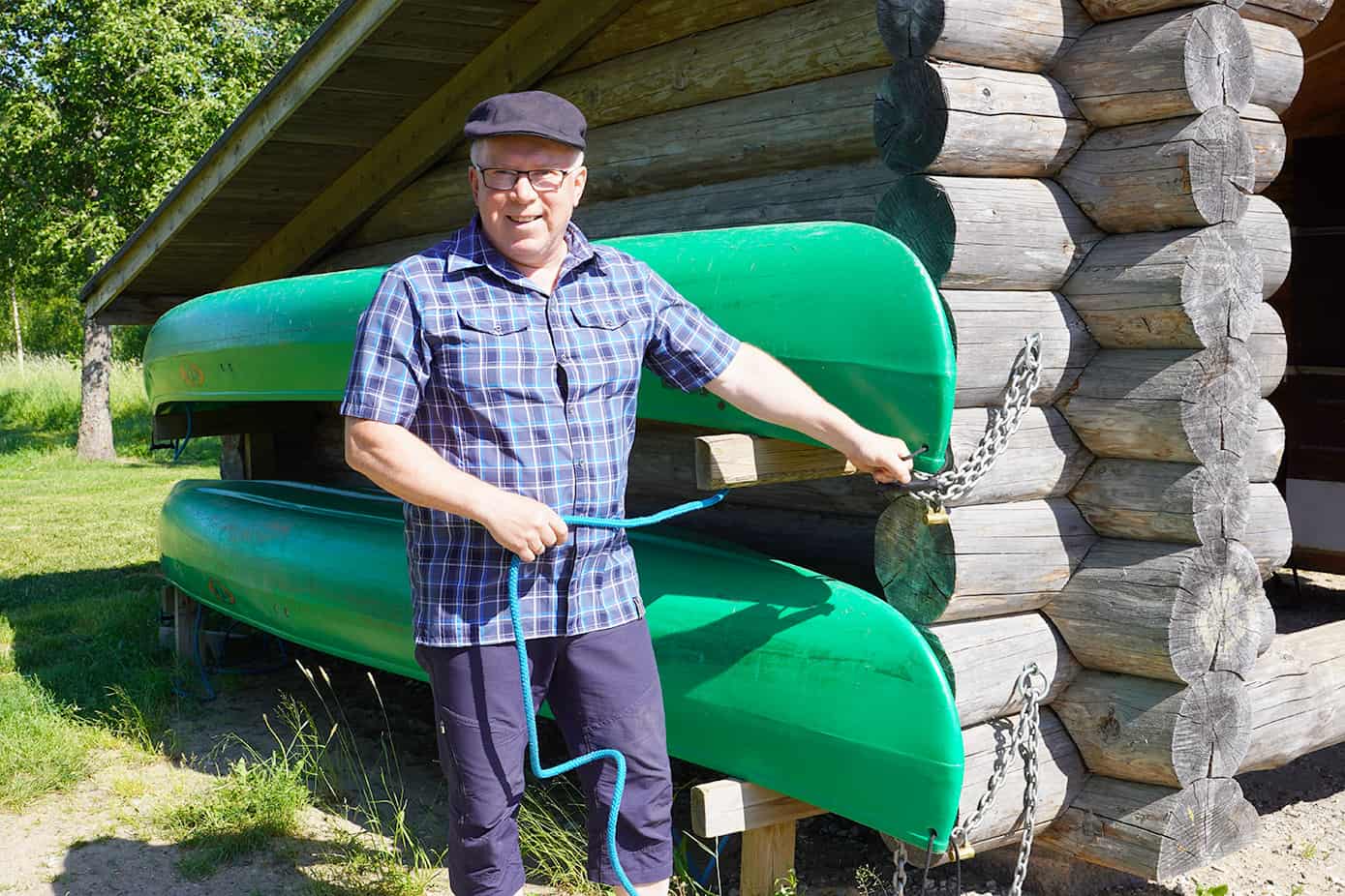 Mies seisoo kahden vihreän kanootin vieressä.