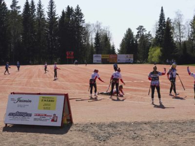 Pöytyän Urheilijoiden naisten Ykköspesis-joukkue pelaa pesäpalloa LED-mainostaulun takana.