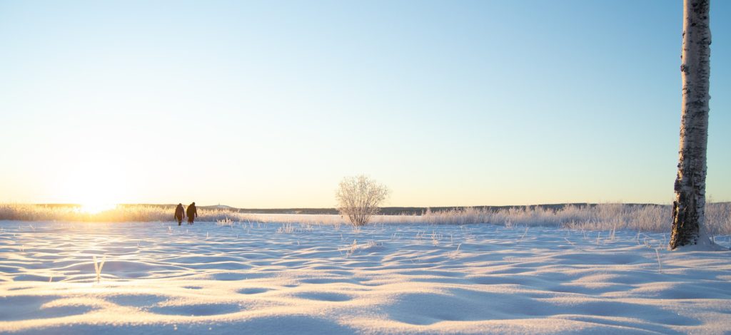 Talvinen maisema, jossa näkyy kaksi ihmishahmoa kaukana.