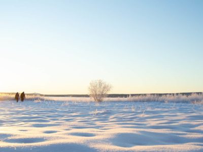 Talvinen maisema, jossa näkyy kaksi ihmishahmoa kaukana.